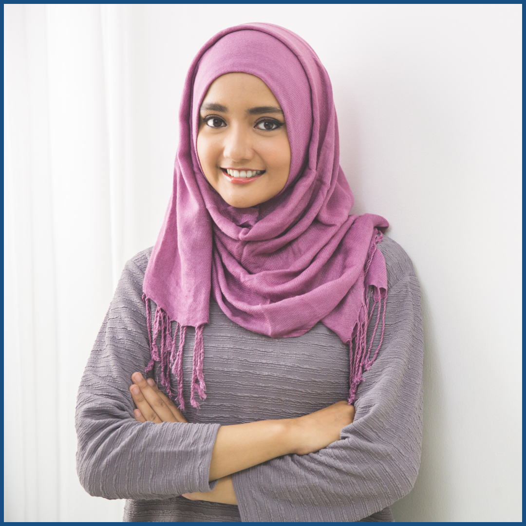 a muslim woman smiling with her arms crossed.